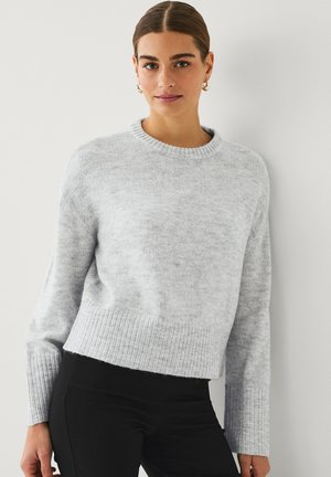 Light gray knit sweater with a round neckline, ribbed cuffs, and hem. Soft texture, relaxed fit, and slightly cropped design.