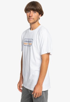 Hvid kortærmet t-shirt lavet af bomuld, prydet med et farverigt "Quiksilver" logo i et rektangulært design hen over brystet.