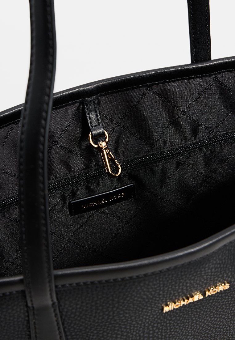 Zwarte leren tote bag met een getextureerde buitenkant, gevoerde quiltstof met logo en een ritsvak met gouden hardware.