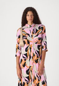 Napukdress dengan pola abstrak multicolor dalam warna merah muda, oranye, dan hitam, dilengkapi dengan lengan tiga perempat dan kerah. Tekstur kain yang halus.