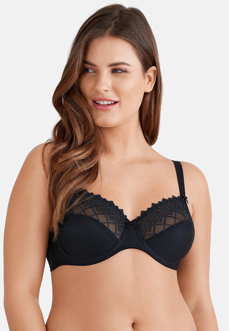 Reggiseno nero con una parte superiore in pizzo con motivi geometrici, bordi ondulati e spalline regolabili. Tessuto liscio sulla coppa inferiore.