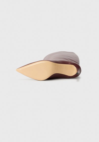 Chaussure à talon haut bordeaux avec un bout pointu et une texture en cuir lisse ; elle présente un talon stiletto beige et un design minimaliste.