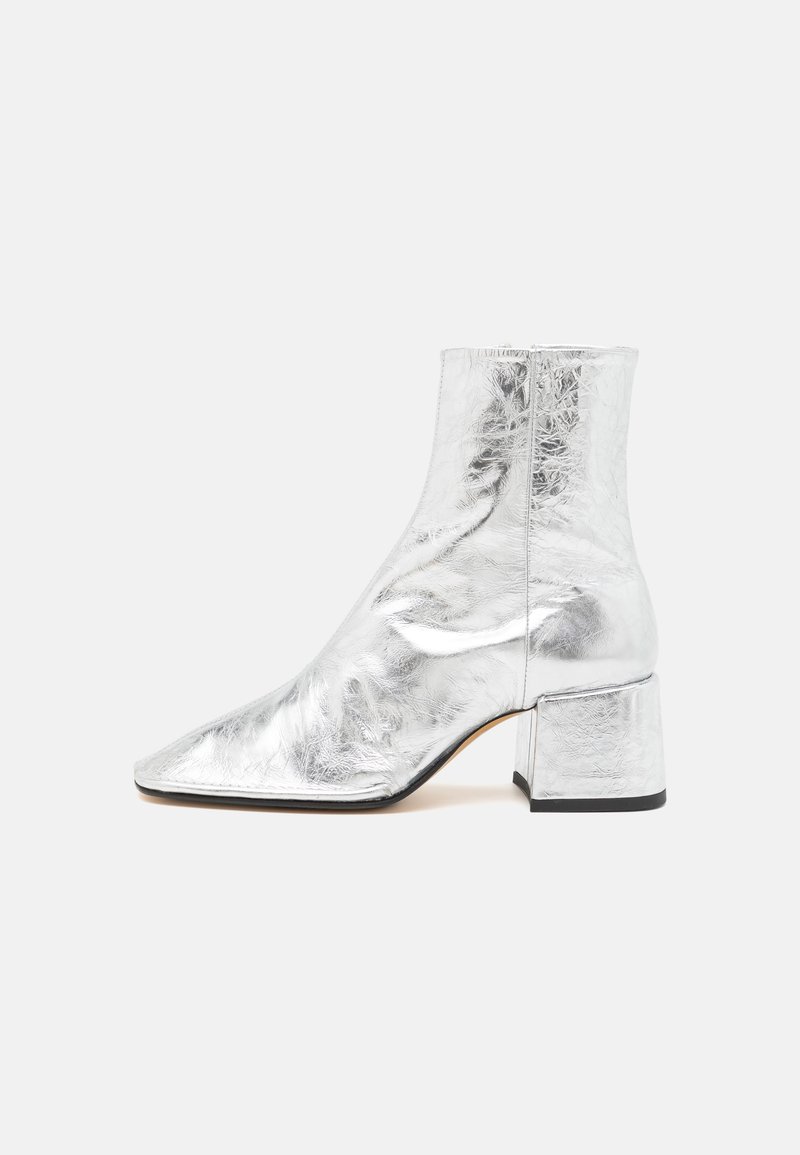 Botas de tobillo plateadas con punta afilada, acabado metálico brillante y tacón bloque. Textura suave con un detalle de costura mínimo.