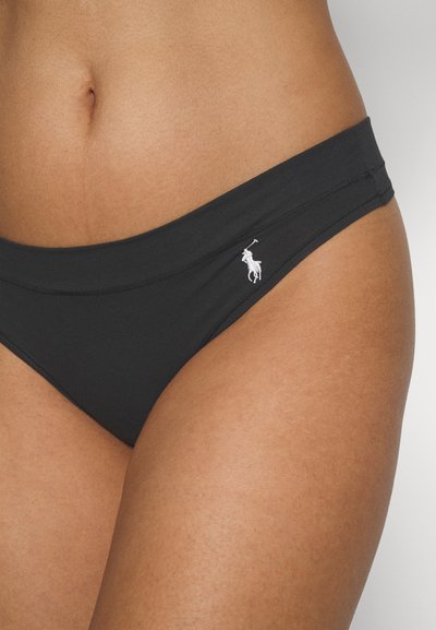 Melnas bikini bikses, kas izgatavotas no gludas materiāla, ar plašu jostu un mazu, baltu izšuvumu logotipu sānos.