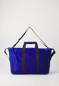 Blue waterproof duffel bag with black webbing straps and a sturdy handle, featuring a large main compartment and adjustable shoulder strap.