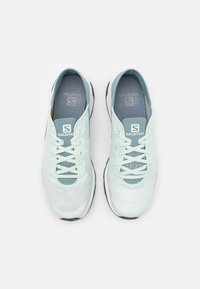 Light green athletic shoes with a breathable mesh upper, laces, and a cushioned sole. Features subtle branding and a sleek design.