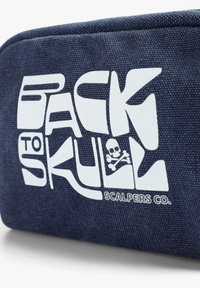 Denim pung med et stort hvidt grafisk tryk, der læser "BACK TO SKULL", samt et skelet og korslagte ben. Robust tekstur med lynlås.
