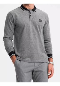 Polo gris à manches longues avec col rayé noir et blanc, patte de boutonnage à trois boutons et logo brodé sur la poitrine.