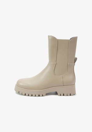 Stivaletti beige in pelle liscia con pannelli laterali elastici, suola in gomma testurizzata e una linguetta sul retro per facilitarne l'indossamento.