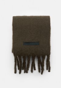 Sötétzöld sál, puha anyagból, bojtokkal ellátva, és egy kis fekete címkével, rajta szöveggel. Téglalap alakú, texturált felülettel.