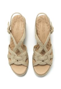 Sandali intrecciati beige con cinturini avvolgenti e soletta in pelle. Cinturino regolabile sul tallone, suola piatta con un motivo testurizzato.