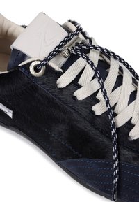 Navy sneaker featuring faux fur and suede materials, with cream laces and a patterned navy lace. Silver eyelet on side for additional detail.