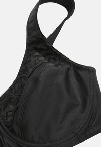 Zwarte bh voor vrouwen met kantdetails aan de zijkant, voorgevormde cups en verstelbare schouderband op een witte achtergrond.