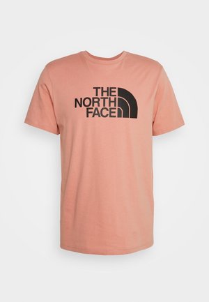 Vaalean korallinvärinen lyhythihainen T-paita, jossa musta "THE NORTH FACE"-teksti ja logo keskellä edessä.