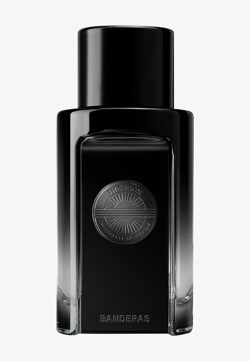 Flacon de parfum rectangulaire noir avec un emblème rond portant l'inscription "The Icon" et "Success is an attitude", étiqueté "Banderas".