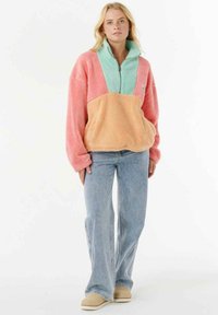 Fleece pullover with a quarter-zip, featuring pink, mint green, and peach colors. Oversized fit with dropped shoulders and a soft texture.