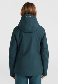 Teal waterproof jacket with a hood, featuring a smooth texture and a logo detail on the collar. Back view, accompanied by matching pants.