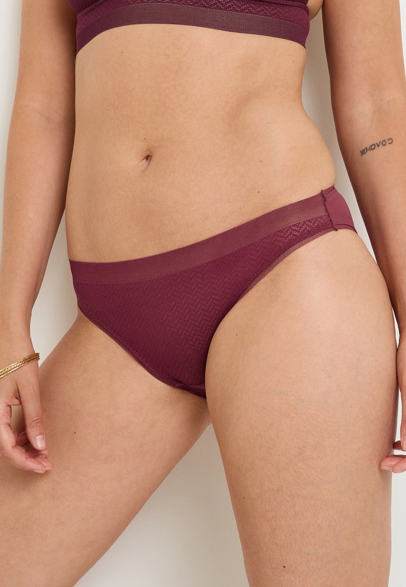 Bikini intimo in rete bordeaux con vita liscia, caratterizzato da un delicato motivo a zigzag e tessuto elastico e traspirante.
