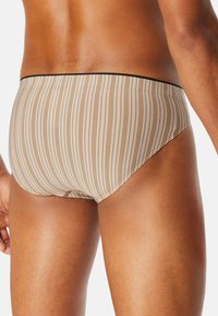 Herren-Schwimmshorts in Beige mit vertikalen weißen Streifen, ausgestattet mit einem schwarzen elastischen Bund und einer glatten Textur.