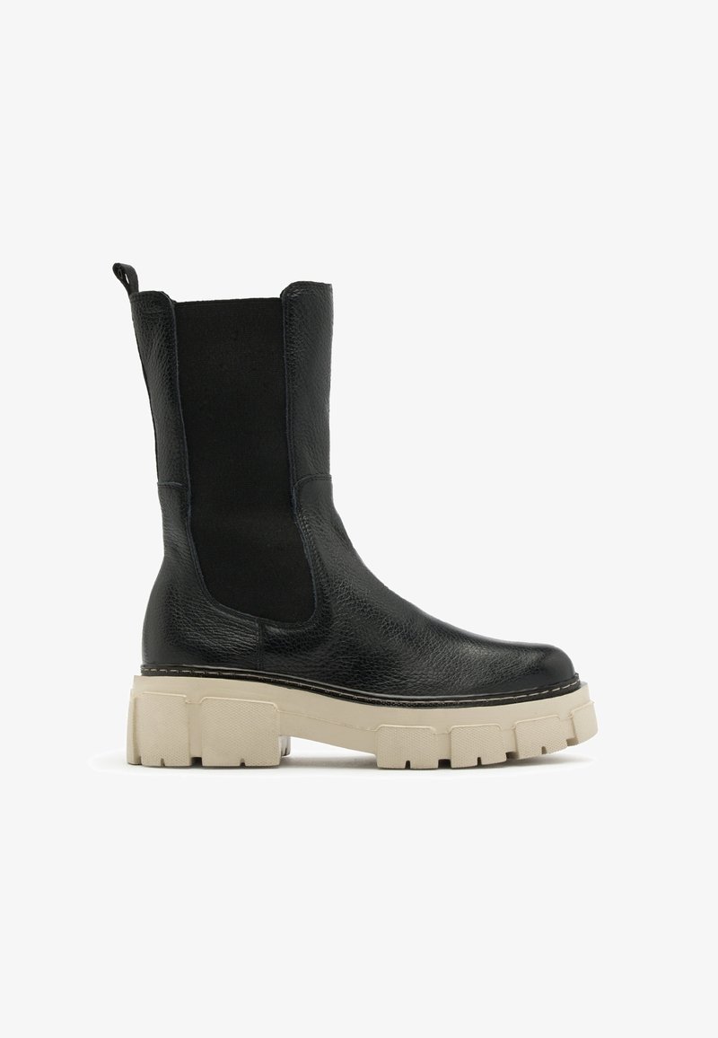 Botte en cuir noir mi-mollet avec une semelle beige épaisse et grossière, panneaux latéraux élastiques, et languette d'extraction à l'arrière.