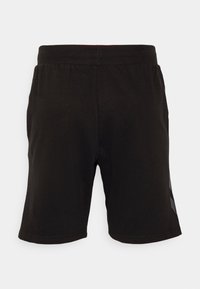 Pantalones cortos deportivos de algodón negro con cinturilla elástica y rayas laterales. De longitud corta y textura suave, diseñados para la comodidad.