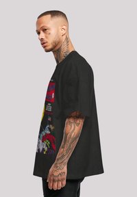 Black oversized T-shirt featuring colorful comic book graphics. Cotton material with short sleeves, relaxed fit, and a round neckline.