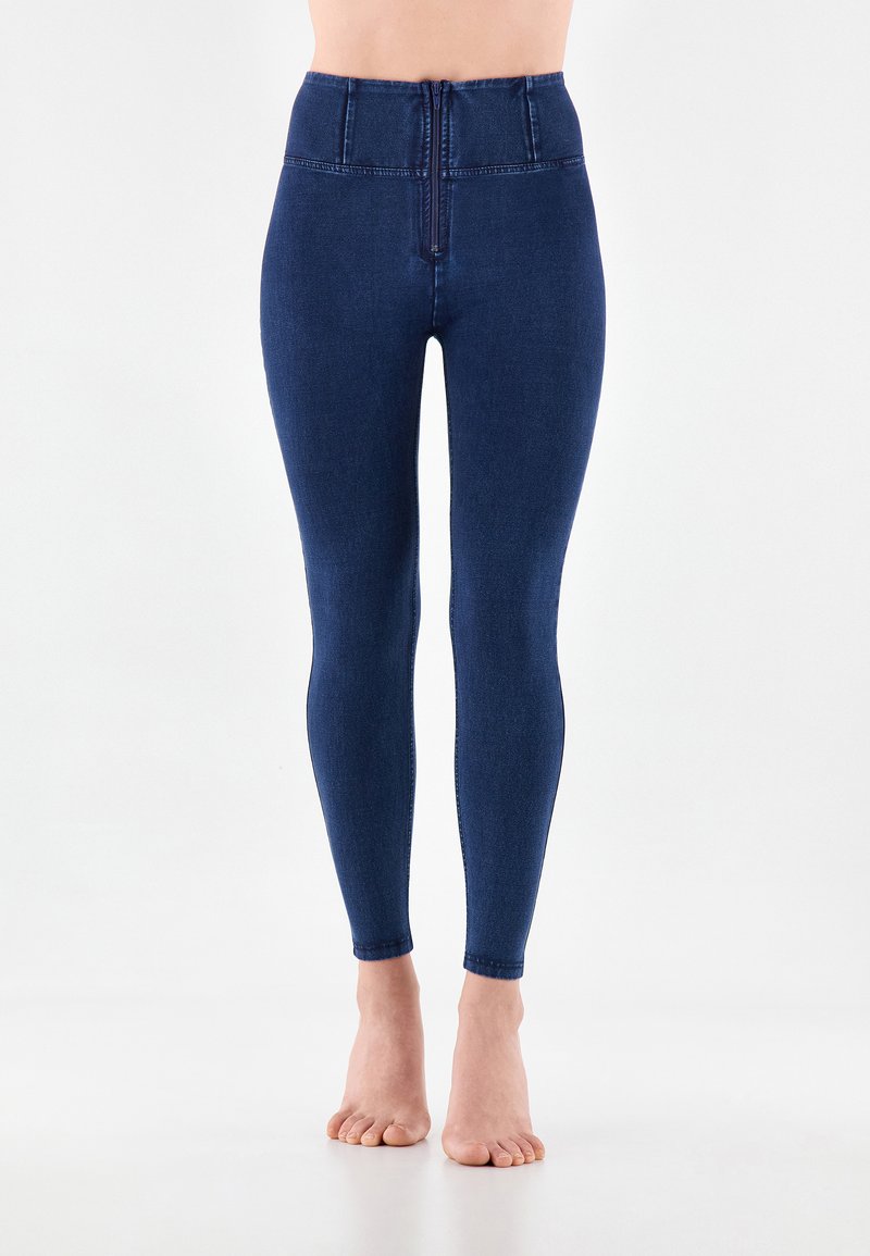 Korkeavyötäröiset tummansiniset denimit legginsit, joissa on sileä pinta, kapea leikkaus ja vähäiset ompeluyksityiskohdat vyötäröllä ja nilkoissa.