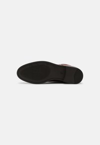 Suola di una scarpa elegante in pelle marrone con suola in gomma nera testurizzata, taglia 37 contrassegnata, e un sottile logo circolare sulla parte anteriore.