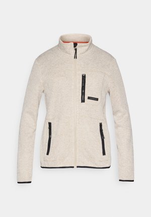 Hellbeige Fleecejacke mit strukturiertem Fischgrätmuster, schwarzen Reißverschlüssen und einem orangefarbenen Innenfutter. Verfügt über einen hohen Kragen und mehrere Taschen.