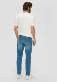 Vervaagde blauwe jeans met een rechte pijp, gecombineerd met een eenvoudige witte t-shirt. Minimalistisch ontwerp, geen zichtbare patronen of hardware.