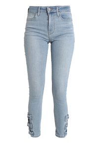 Jeans skinny de color azul claro con cintura alta, bolsillos frontales y lazos decorativos a lo largo de la parte exterior de las piernas inferiores.