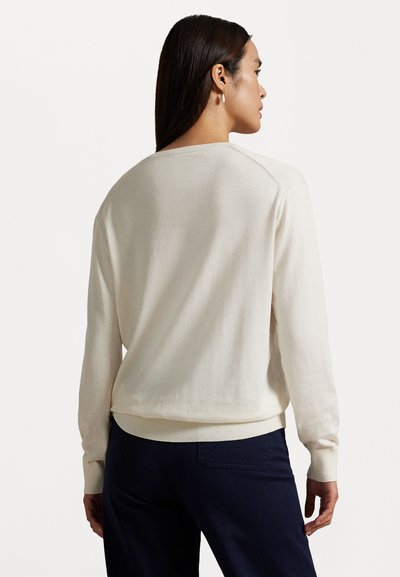 Hellbeige Pullover mit langen Ärmeln, geripptem Rundhalsausschnitt und Saum. Weiche Textur, lässige Passform und sauberes, schlichtes Design.