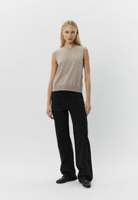 Beige ærmeløs strikketop parret med sorte vidde bukser og sorte strop sandaler med nitter; glat stof, casual pasform, minimalistisk design.