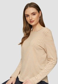 Beige langemouwtop met witte horizontale strepen. Zacht materiaal met een ronde halslijn en een relaxte pasvorm, voorzien van gestikte zomen en manchetten.