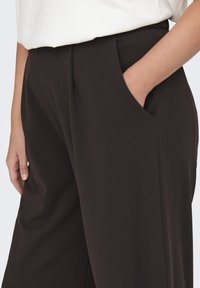 Pantalones negros con una textura suave, con bolsillos laterales y un corte relajado. La cintura es elástica para mayor comodidad.