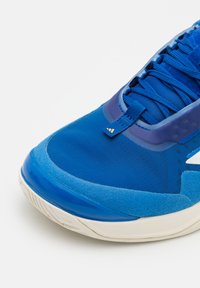 Scarpa atletica blu realizzata in materiali in mesh e camoscio, con una soletta intermedia liscia e lucida, lacci testurizzati e un discreto dettaglio del logo.