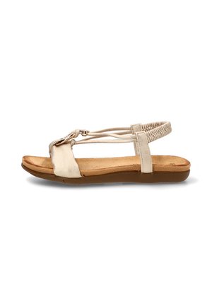 Sandalia plana beige con plantilla acolchada, tiras elásticas en el tobillo y hebilla decorativa en la tira delantera sobre fondo blanco.