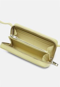 Żółty skórzany portfel z zamkiem błyskawicznym, zawierający wiele kieszonek na karty i zamykaną na zamek komorę. Gładka tekstura i minimalistyczny design.