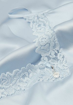 Jasnoniebieska satynowa tkanina z kwiatową koronkową lamówką i małym srebrnym zawieszonym w kształcie serca przy brzegu.