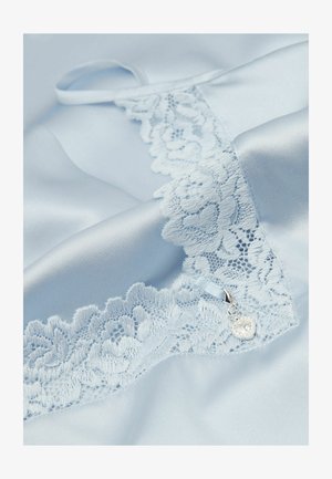 Jasnoniebieska satynowa tkanina z kwiatową koronkową lamówką i małym srebrnym zawieszonym w kształcie serca przy brzegu.