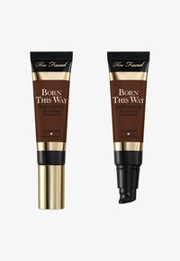 Two brown tubes of Too Faced foundation, labeled "Born This Way Soft Matte." Gold accents, one with a pump and the other with a screw cap.