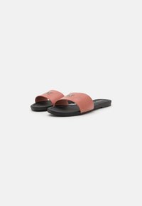 Infradito rosa con materiale liscio, ampie cinghie superiori e suola nera. Presentano un accento in metallo sul cinturino anteriore.