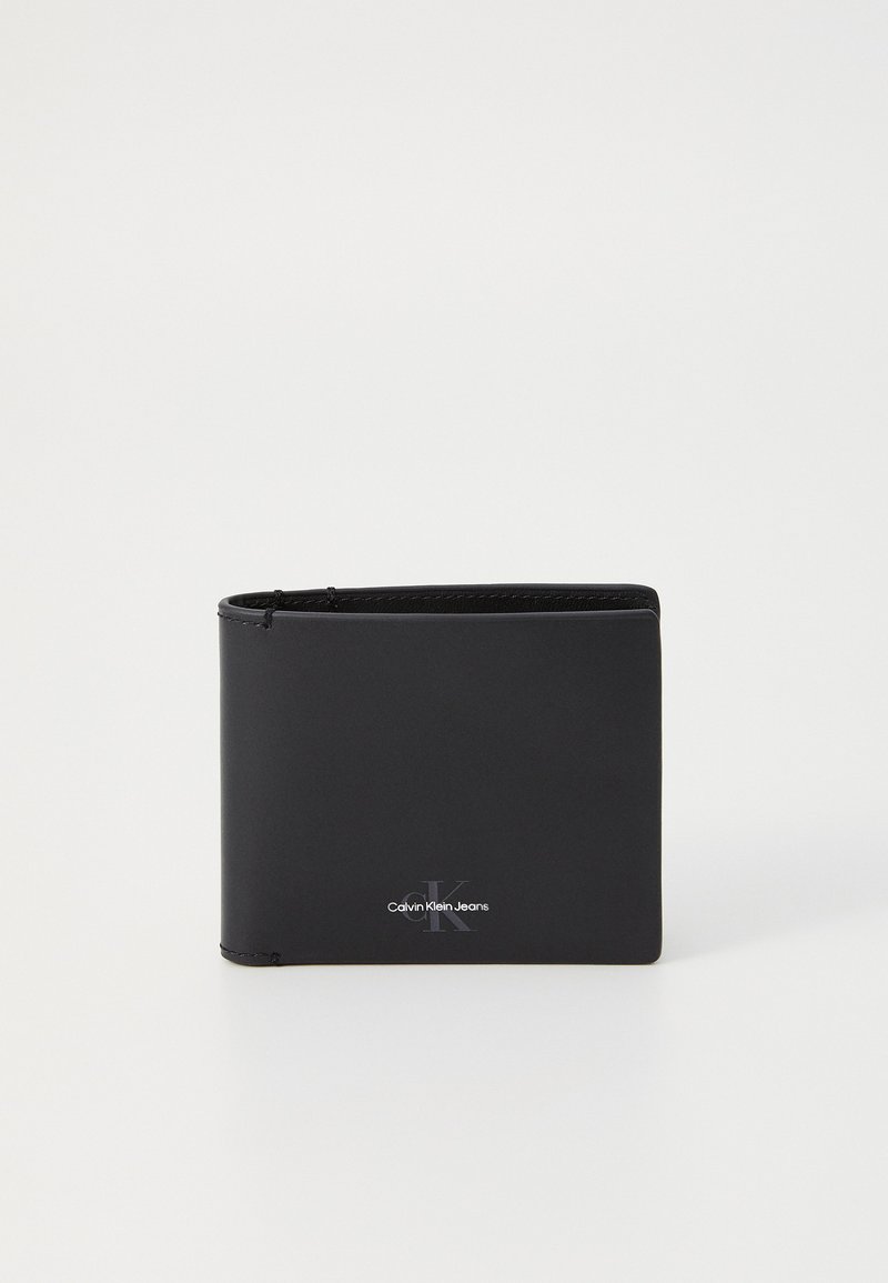 Svart läderplånbok med rektangulär form. Har en Calvin Klein Jeans-logotyp och synliga sömdekorationer. Slät yta.