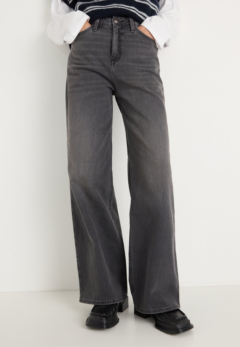 Posede grå denim jeans med høj talje, forlommer og en robust tekstur, parret med sorte platforniersko.