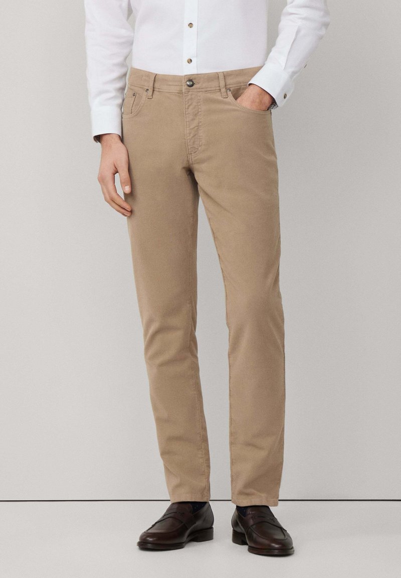 Beige katoenen broeken met een rechte pasvorm, voorzien van een voorknoopzak, een enkele knoopsluiting en subtiele stikseldetails.