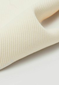 Krémová žebrovaná látka přeložená, což ukazuje jemný, texturovaný povrch s jemnými liniemi a hladkým finišem.