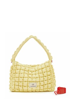 Bolso acolchado amarillo con textura acolchada, un asa superior y una correa roja para el hombro removible al lado.
