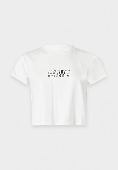 Άσπρο κοντομάνικο crop top t-shirt με μαύρο τυπωμένο σχέδιο ημερολογίου στο κέντρο του στήθους που δείχνει τον αριθμό έξι περικυκλωμένο.