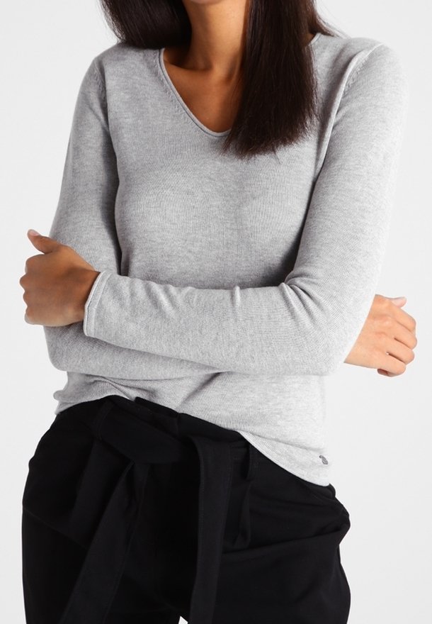 Maglia a maniche lunghe grigio chiaro con scollo a V, texture a coste e silhouette aderente, abbinata a pantaloni neri con cintura annodata.