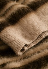 Gyapjú pulóver váltakozó barna és bézs csíkokkal, bordázott mandzsettákkal, puha tapintással és enyhén bolyhos megjelenéssel.